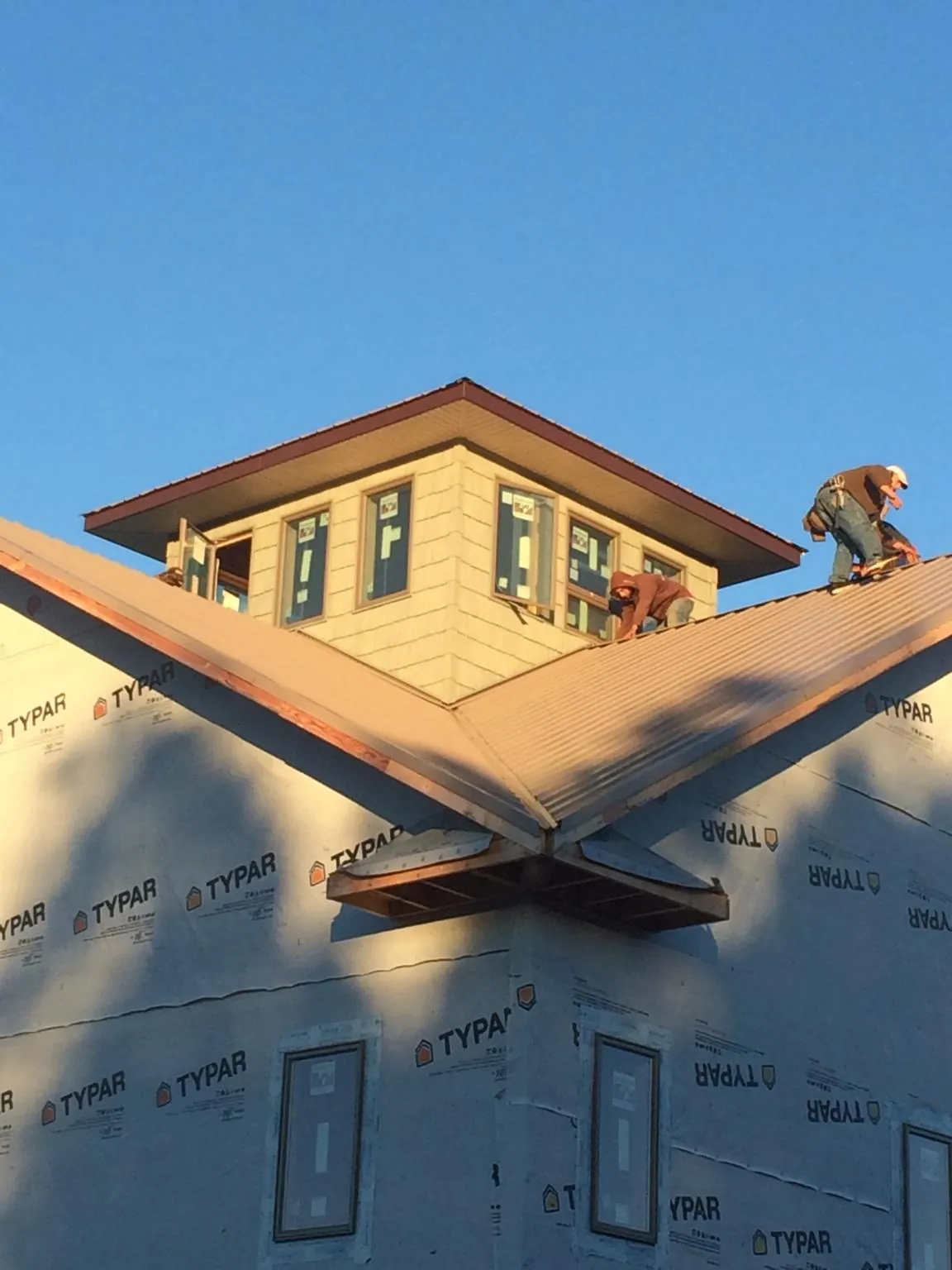 Roofers working around a rooftop cupola on a new metal roof at sunset — Roof Waterproofing in Garden City by Roofing Brothers